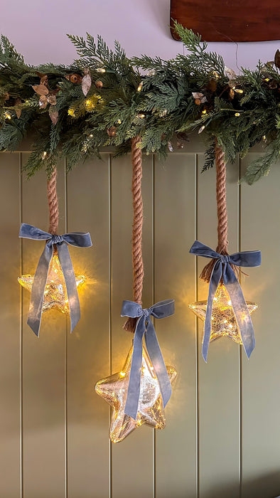 Mercury glass LED stars in different sizes styled beneath Christmas greenery
