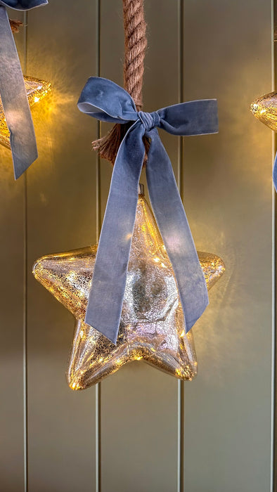 Illuminated mercury glass star hanging with a blue velvet bow