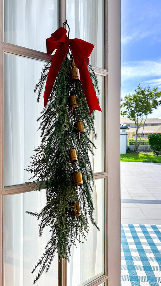 100cm Christmas swag with golden bells styled on a glass door with a red velvet bow