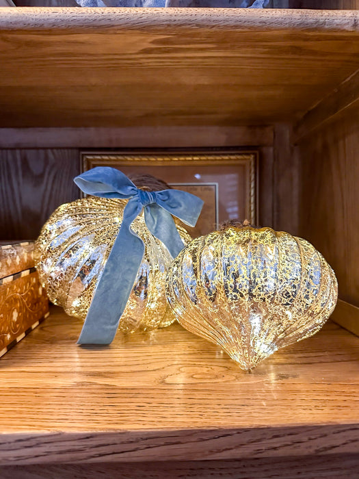 Illuminated mercury glass onion ornaments in coordinating sizes with a blue velvet bow