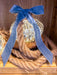 Close-up of an illuminated mercury glass onion ornament styled with rope and a blue velvet bow