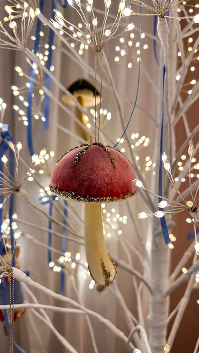 Pink velvet hanging mushroom ornament displayed on an illuminated white Christmas tree