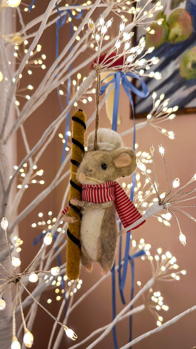 Felt mouse holding a cookie roll on an illuminated white Christmas tree