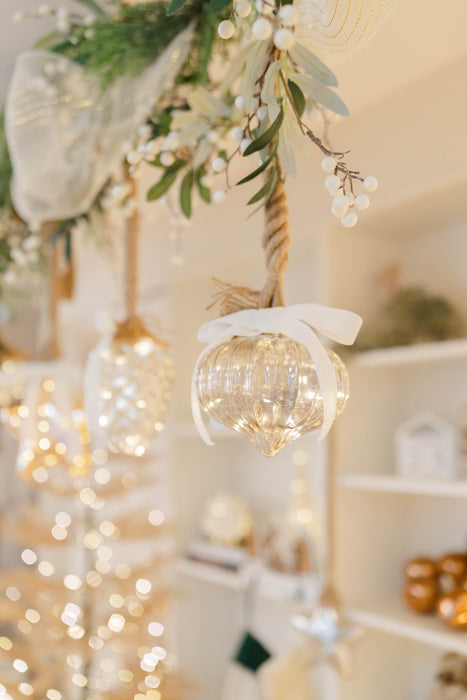Illuminated mercury glass onion ornament hanging with a white velvet bow
